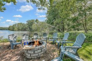 a group of chairs around a fire pit by the water at Lakefront Big Bass Lake Dock Games in Gouldsboro