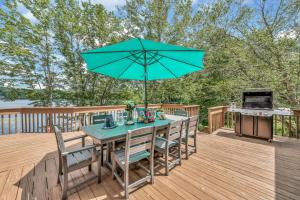 a table with an umbrella on a deck with a grill at Lakefront Big Bass Lake Dock Games in Gouldsboro