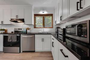 a kitchen with white cabinets and black appliances at Lakefront Big Bass Lake Dock Games in Gouldsboro