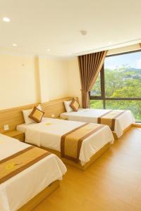 Una habitación de hotel con tres camas y una ventana. en Đức Khôi Hotel, en Cao Bằng