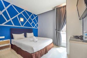 a bedroom with a bed with a blue wall at Swing & Pillows - Kota Damansara in Kota Damansara