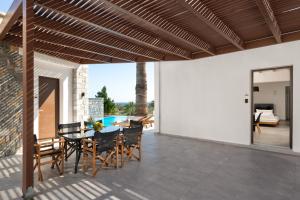 a patio with a table and chairs and a pool at Terra Pietra Luxury Villas & Suites in Lardos