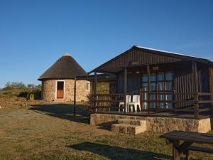 a building with a thatch roof with two white chairs in front at Jagerskraal Guest Farm in Laingsburg