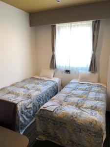 two beds in a room with a window at Murayama Nishiguchi Hotel in Murayama +17 photos