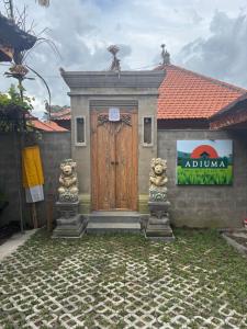 ein Gebäude mit einer Holztür mit zwei Statuen in der Unterkunft Adiuma Cottage Ubud in Ubud