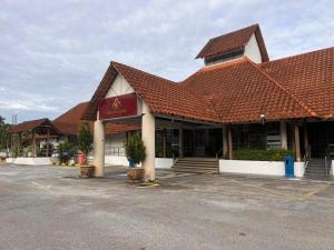 Un edificio con techo rojo en un estacionamiento. en Hotel De Cassia, en Kampar