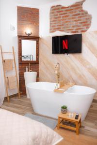 a bathroom with a white tub and a tv on the wall at Marcos Apartments I Bathtub in Bedroom experience in Făgăraş
