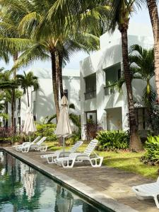 a resort with a swimming pool with chairs and palm trees at La Residence by LOV Mauritius in Midlands Station +17 photos