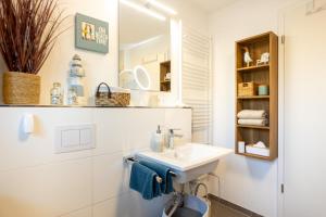 a white bathroom with a sink and a mirror at NordseeResort Tossens - Seaside Corner in Tossenserdeich