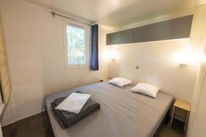 a bedroom with a bed with two pillows and a window at ZEcamping 5 étoiles familial animaux acceptés in Sainte-Catherine-de-Fierbois