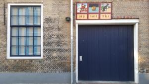 a blue garage door on the side of a brick building at Lant van Beloften in Vlissingen