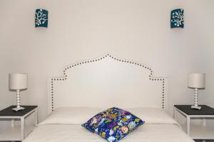 una camera con un letto bianco e due tavoli con lampade di Hotel Cutimare - Aeolian Charme ad Acquacalda