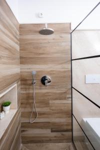 a shower in a bathroom with wooden walls at Marcos Apartments I Bathtub in Bedroom experience in Făgăraş
