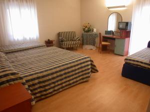 a hotel room with two beds and a desk at Hotel La Pergola in Rionero in Vulture