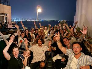een groep mensen die rond een tafel zitten met hun handen omhoog bij Cheers Vintage Hostel in Istanbul