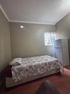 a bedroom with a bed and a refrigerator at The Easy Stay in Durban