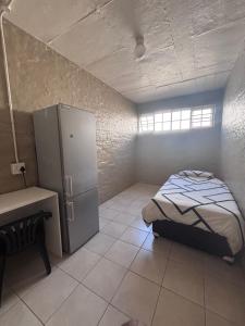 a small bedroom with a bed and a refrigerator at The Easy Stay in Durban +5 photos