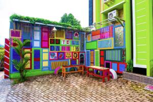 a colorful building with two tables and two benches at SPOT ON 2815 Hotel Damai in Cilacap