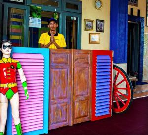 a man standing behind a counter with a superhero doll at SPOT ON 2815 Hotel Damai in Cilacap