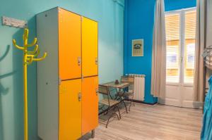 Un casillero naranja y gris en una habitación con una mesa. en Victoria House Hostel, en Génova