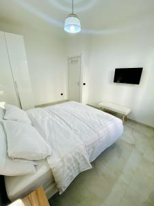 une chambre blanche avec un lit blanc et une télévision dans l'établissement Corso 42, à Novara 2 autres photos