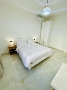 - une chambre blanche avec un lit blanc et 2 tables dans l'établissement Corso 42, à Novara