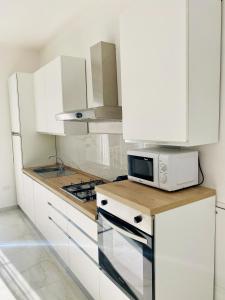 Il comprend une cuisine blanche équipée d'un four micro-ondes et d'une cuisinière. dans l'établissement Corso 42, à Novara