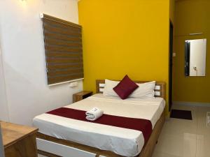 een slaapkamer met een bed met een gele muur bij Calicut residency in Kozhikode +1 foto