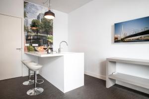 a white kitchen with a sink and a stool at Maurits Apartments & Suites in Rotterdam +49 photos