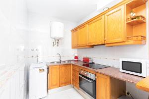 a kitchen with wooden cabinets and a white refrigerator at apartamento Cabo de Gata in El Cabo de Gata