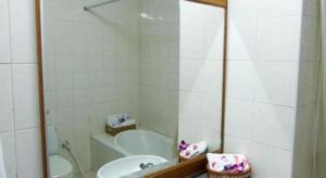 Un baño con bañera, lavabo y espejo. en Sakol Grand Palace Hotel, en Sakon Nakhon