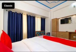 a bedroom with a bed with blue curtains and a tv at Hotel Ratnouday in Kāndi