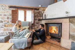een man en vrouw in een woonkamer met een open haard bij Carbayu Senda del Oso in Proaza +81 foto's