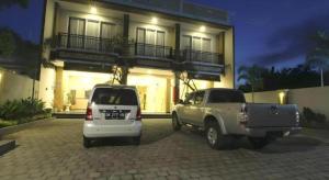 due veicoli parcheggiati di notte di fronte a una casa di MANDARI HOTEL SINGARAJA a Singaraja