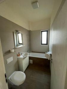 a bathroom with a toilet and a tub and a sink at VISAJ Residence in Timişoara