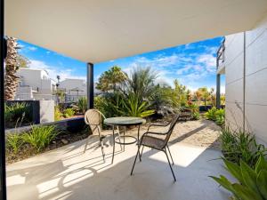a patio with two chairs and a table with a view at Corrigans Poolside Apartment Batehaven in Batehaven