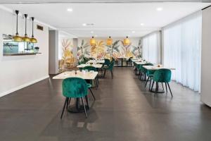 a dining room with tables and green chairs at Corrigans Poolside Apartment Batehaven in Batehaven