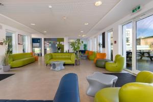 a lobby with green and orange furniture and windows at Haus KLIPPER Norderney in Norderney