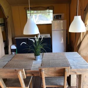 een tafel en stoelen in een keuken met een koelkast bij Camping Le Mondou in Saint-Julien-de-Lampon