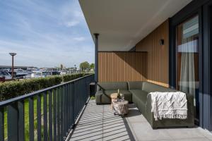 patio con sofá en el balcón en Luxe apartment in recidence marina uithaven 1C, en Kamperland