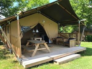 a tent with a table and a picnic table in it at Camping Le Mondou in Saint-Julien-de-Lampon