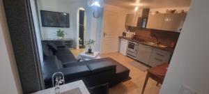 ラ・フェルテ・スー・ジュアールにあるApparemment deux chambresの黒いソファとキッチンのあるリビングルーム