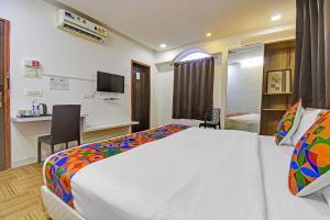 a hotel room with a bed and a desk at FabHotel The Walnut in Pune