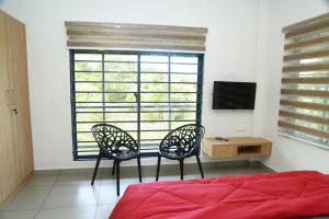 イドゥッキにあるSerene Peaksのベッドルーム1室(椅子2脚、テレビ、窓付)