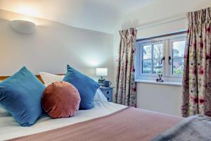 een slaapkamer met een bed met kleurrijke kussens en een raam bij 1 Bed in Snape oc-a30669 in Snape