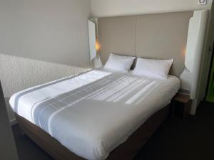1 cama blanca grande con sábanas y almohadas blancas en Campanile Valence Sud, en Valence