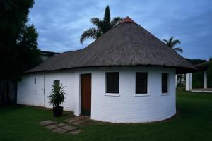 un piccolo edificio bianco con tetto di paglia di Nut Tree Nook a Hazyview