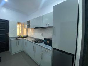 a kitchen with white cabinets and a stove top oven at Rachel's Place in Ibadan