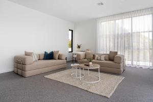 een woonkamer met twee banken en een tafel bij Poolside Luxury Villa - Solar Pool Beach 3min in Mornington +19 foto's