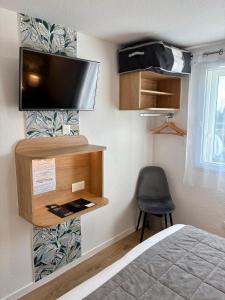 Un dormitorio con una cama y un televisor en una pared. en Hôtel Le Pavillon de Saint-Lô - anciennement Lunotel, en Saint Lo